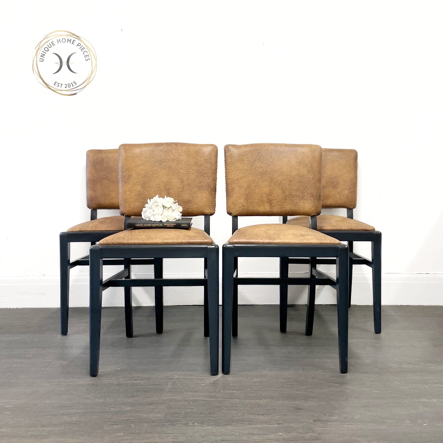 set of 4 black 1950,s  dining chairs by Beautility, upholstered by a professional upholstery  in a faux leather material in a honey tone. these chairs designswill fit perfectly in any dining room while adding a touch of luxury.